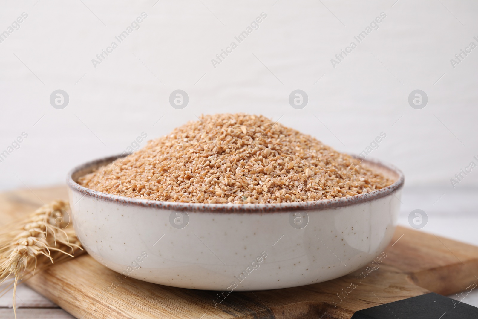 Photo of Dry wheat groats in bowl on table, closeup