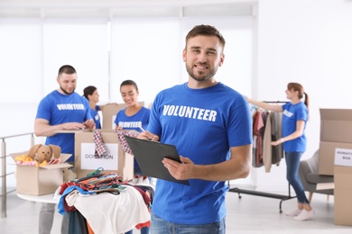 Photo of Male volunteer with clipboard listing donations indoors