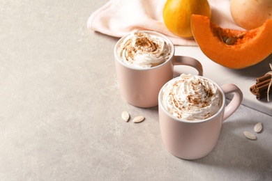 Photo of Cups with tasty pumpkin spice latte and space for text on gray table