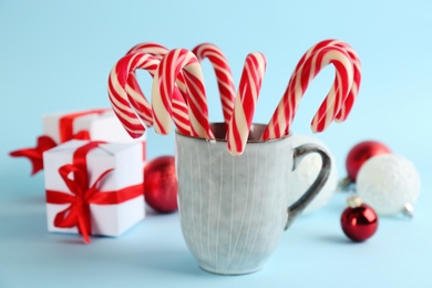 Photo of Christmas candy canes in cup on light blue background