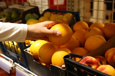 Photo of Woman picking fresh orange at market, closeup
