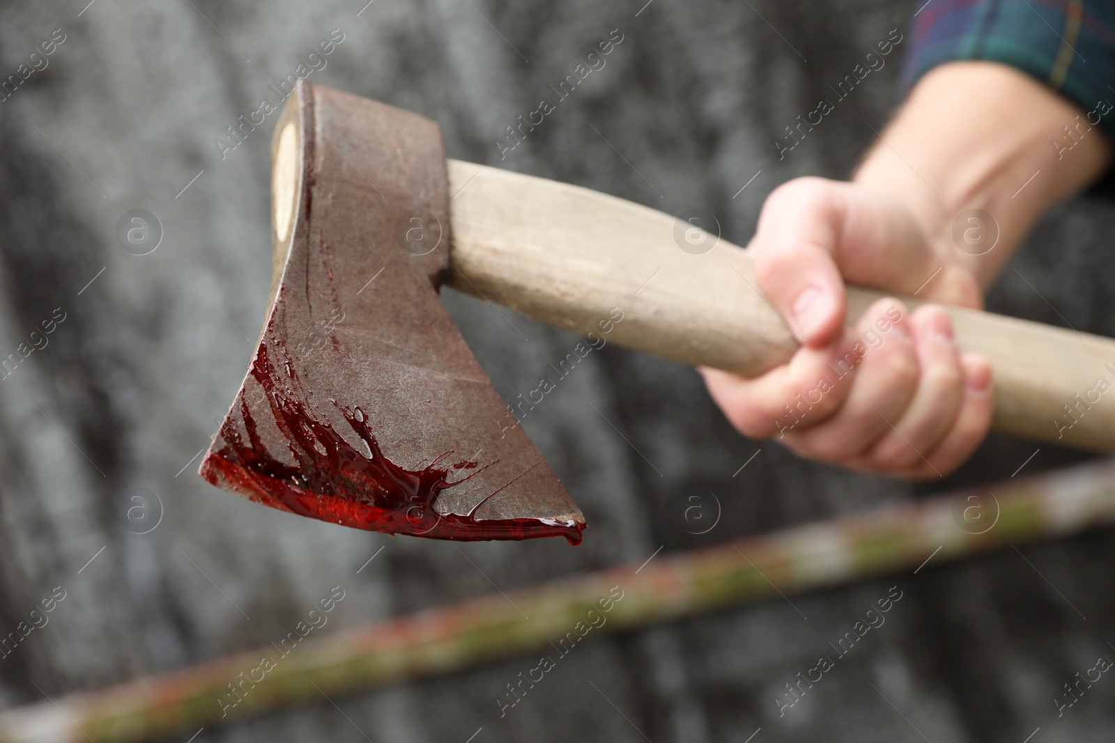 Photo of Man holding bloody axe outdoors, closeup view