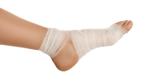 Woman with foot wrapped in medical bandage on white background, closeup