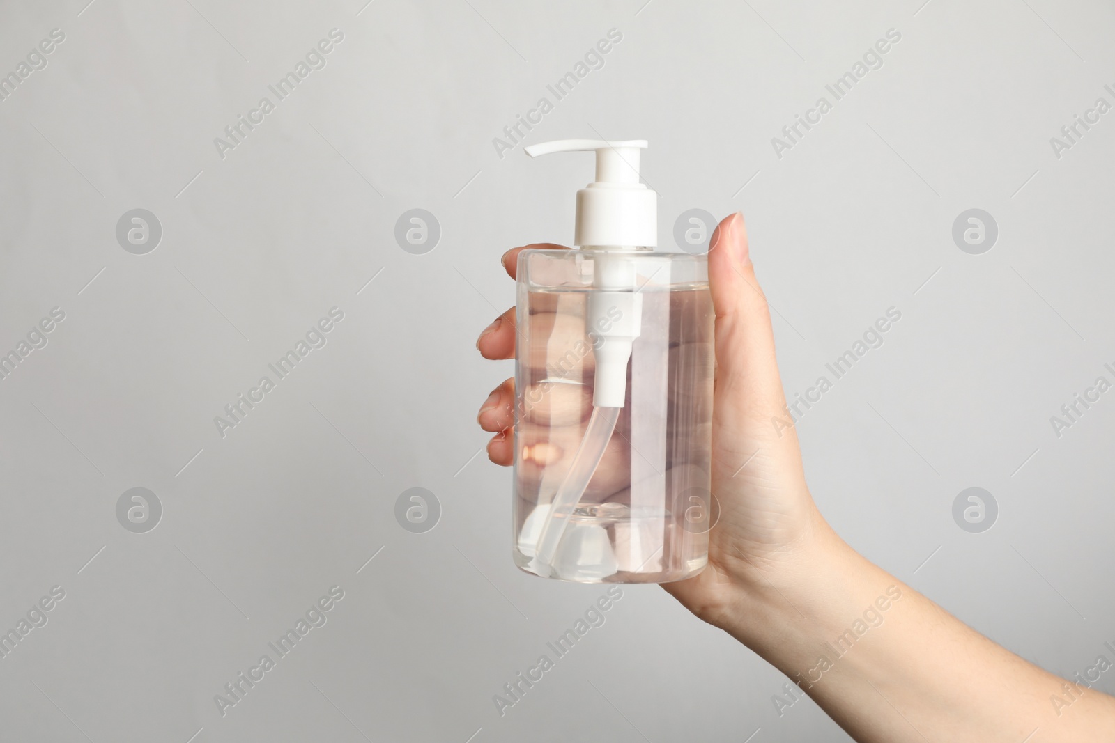 Photo of Woman holding antiseptic gel on light grey background, closeup