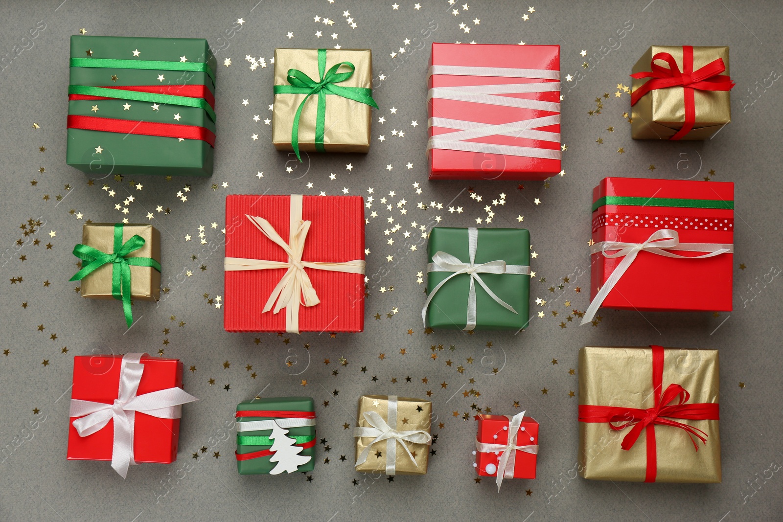 Photo of Flat lay composition with Christmas gift boxes and shiny confetti on grey background