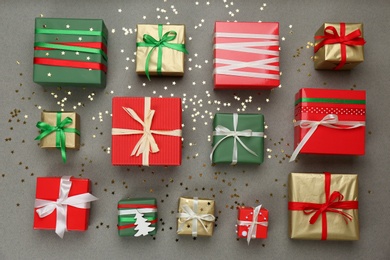 Flat lay composition with Christmas gift boxes and shiny confetti on grey background