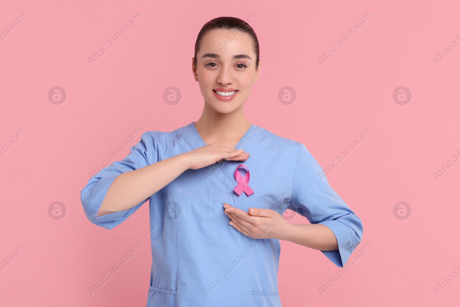 Photo of Mammologist with pink ribbon on color background. Breast cancer awareness