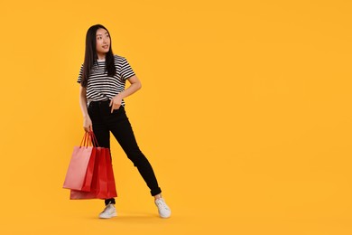 Photo of Smiling woman with shopping bags on yellow background. Space for text