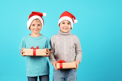 Photo of Cute little children in Santa hats with Christmas gifts on color background
