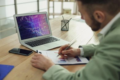 Photo of Broker working with laptop in office, closeup. Forex trading