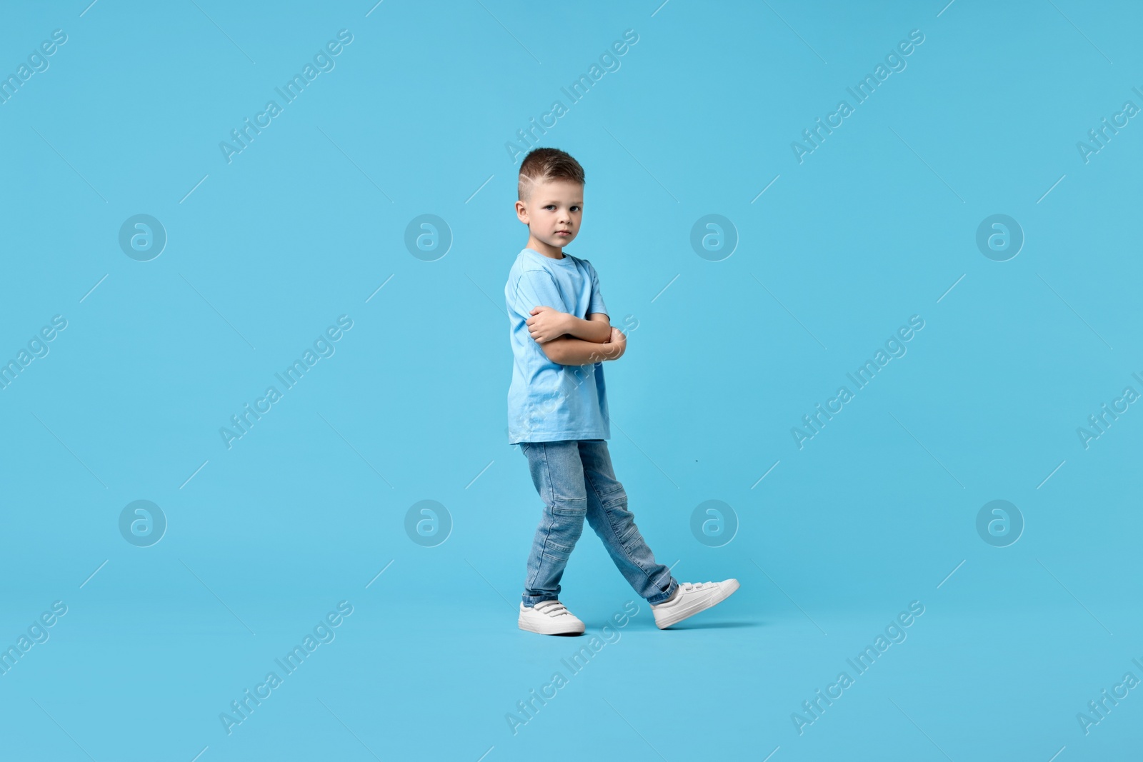 Photo of Happy little boy dancing on light blue background