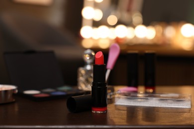 Red lipstick and other beauty products on wooden table. Makeup room