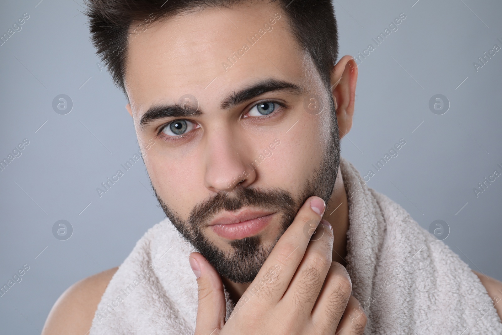 Photo of Handsome young man with beard after shaving on grey background, closeup