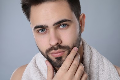 Handsome young man with beard after shaving on grey background, closeup