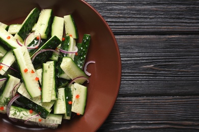 Photo of Plate with delicious cucumber salad on wooden background, top view. Space for text