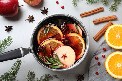 Photo of Saucepan with tasty mulled wine on grey background, flat lay