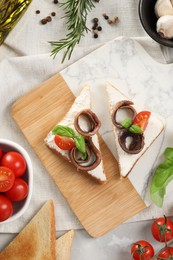 Photo of Delicious sandwiches with cream cheese, anchovies and tomatoes on light grey table, flat lay