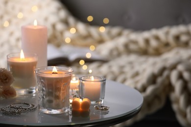 Photo of Burning candles and jewelry on table indoors