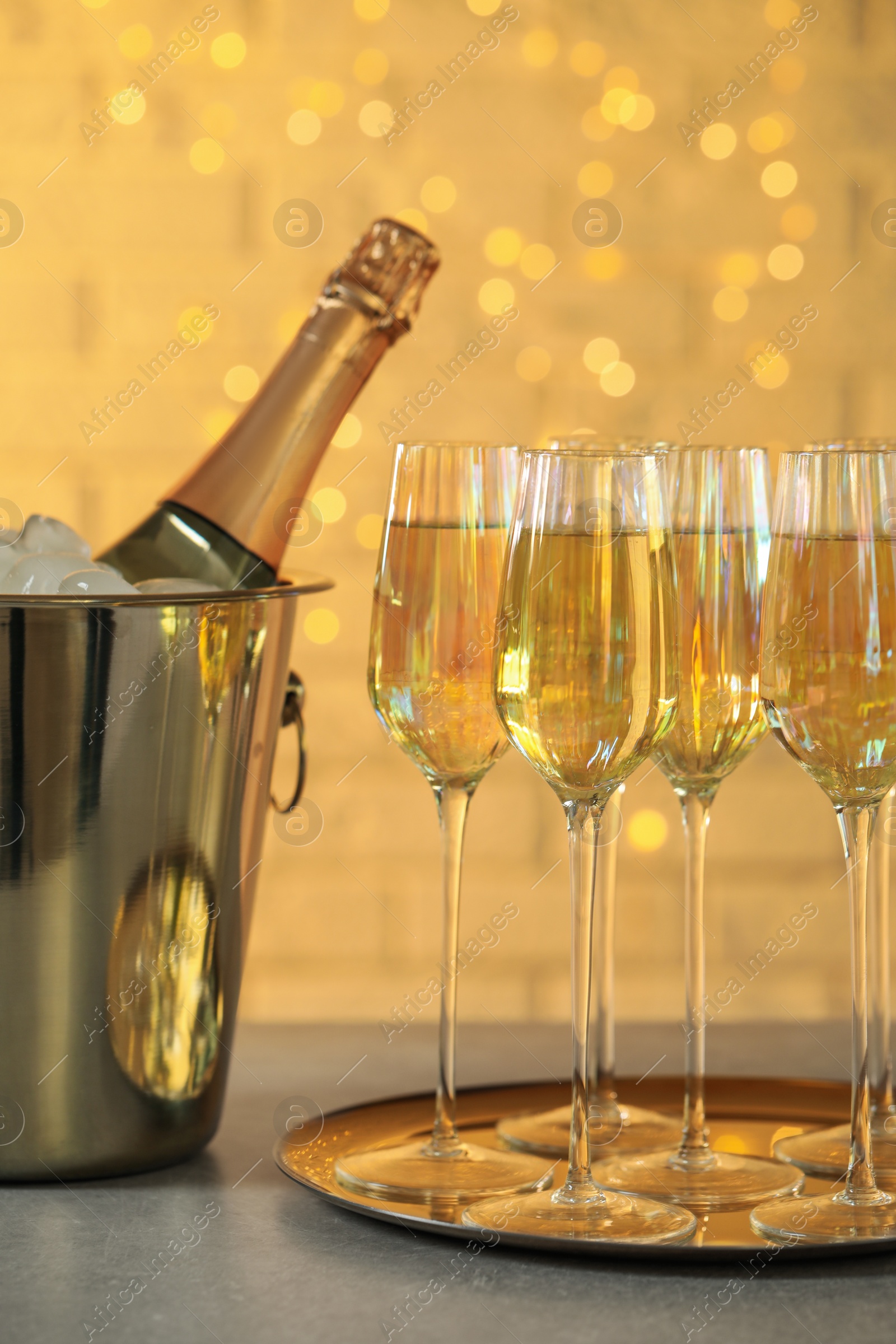 Photo of Glasses of champagne and ice bucket with bottle on grey table