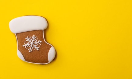 Photo of Christmas stocking shaped gingerbread cookie on yellow background, top view. Space for text