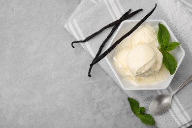 Photo of Delicious ice cream, mint, vanilla pods and spoon on light grey table, flat lay. Space for text
