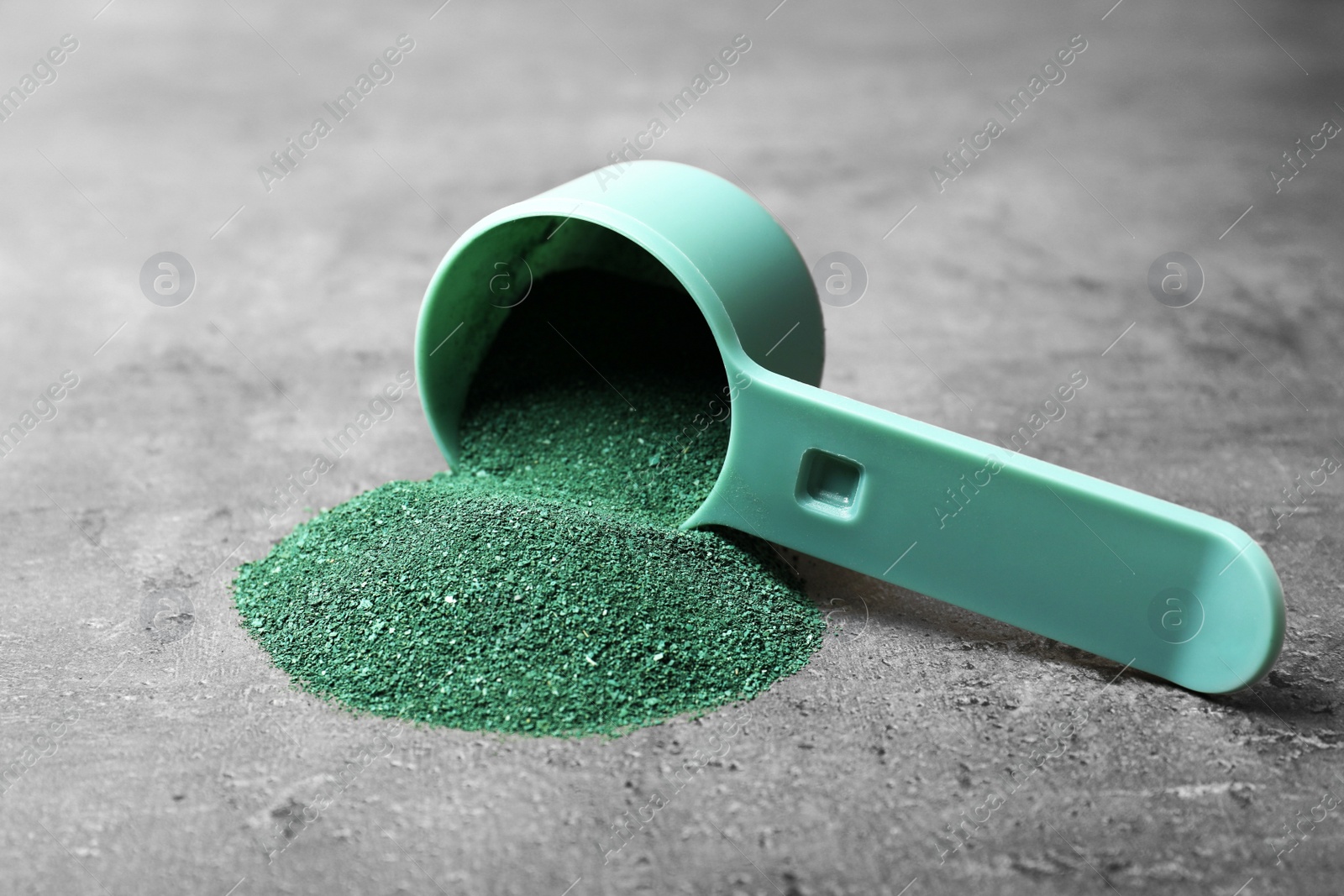 Photo of Scoop and spirulina algae powder on grey background