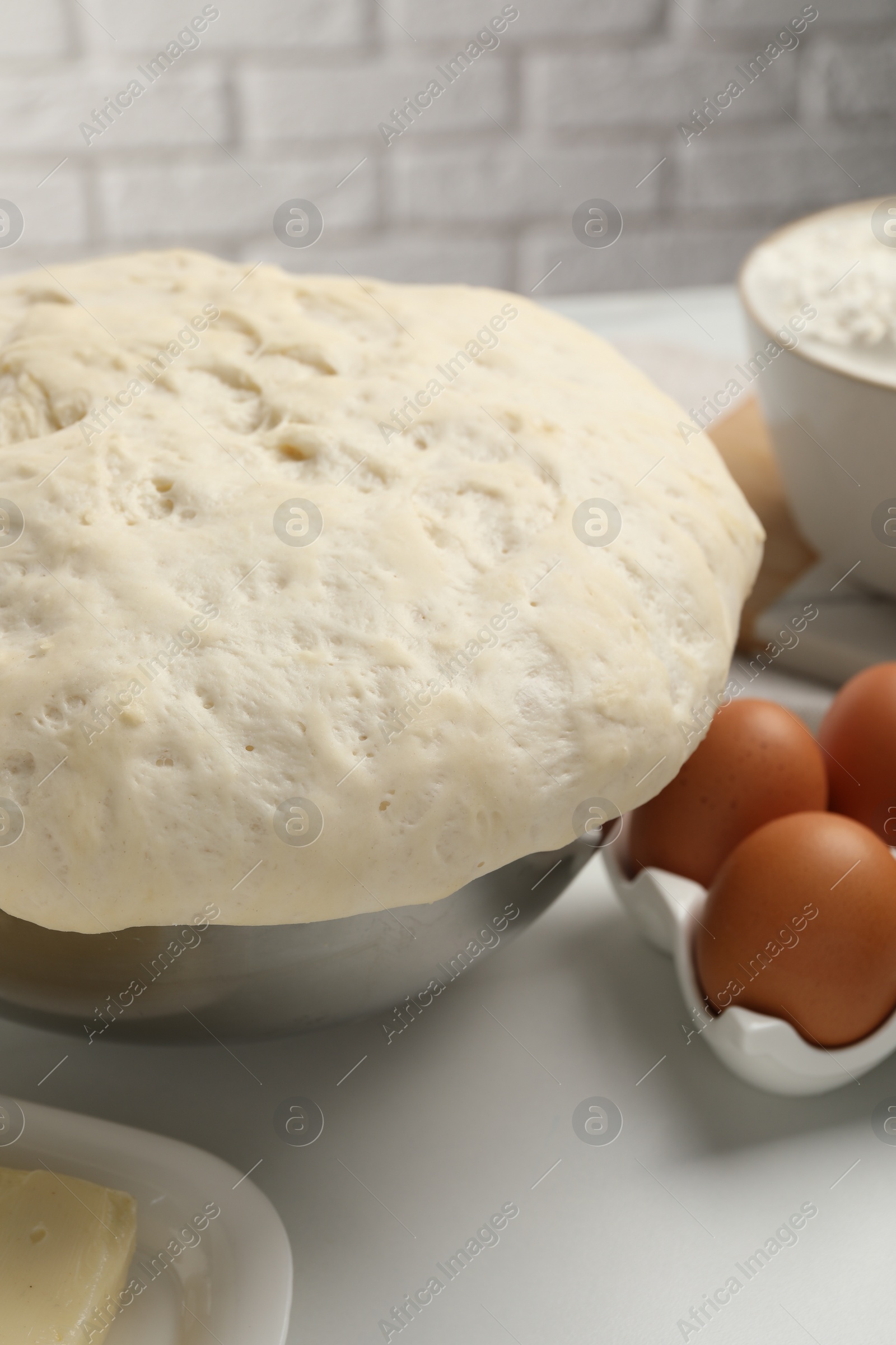 Photo of Fresh dough, eggs and ingredients on white table. Cooking yeast cake
