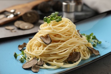 Photo of Delicious pasta with truffle slices and microgreens served on light grey table, closeup