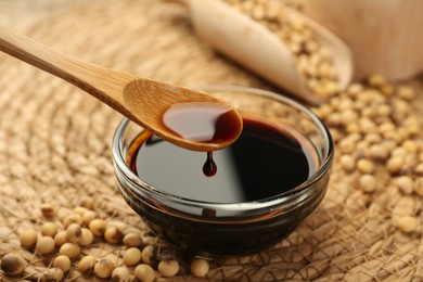 Photo of Taking soy sauce with spoon from bowl at table, closeup