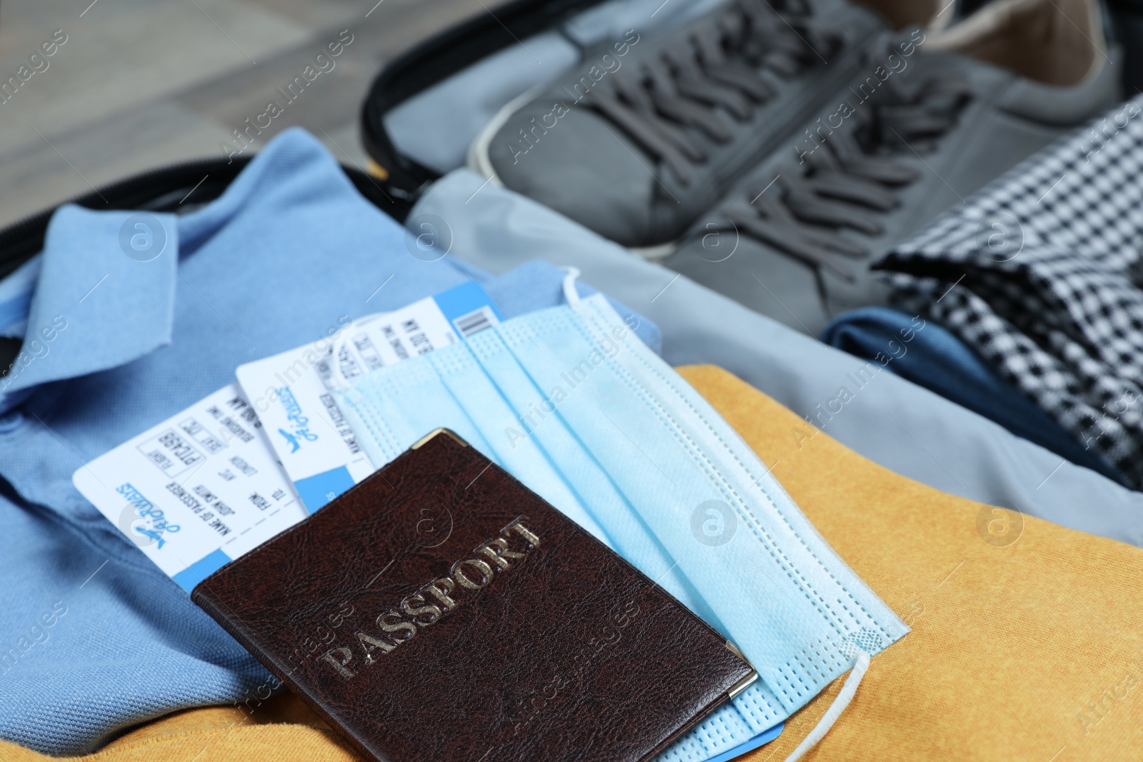 Photo of Passport with protective mask and tickets in suitcase