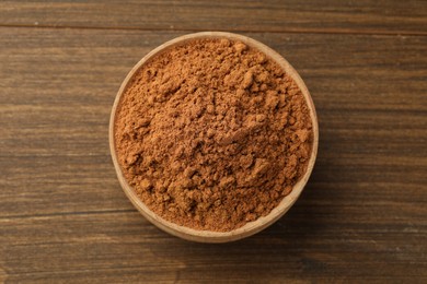 Photo of Aromatic cinnamon powder on wooden table, top view