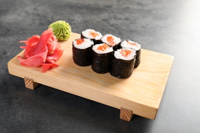 Serving board with tasty sushi rolls on grey table. Food delivery