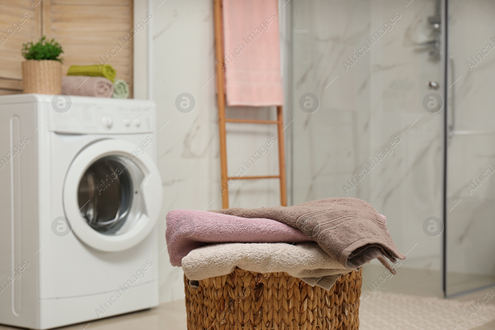 Photo of Wicker basket with laundry and washing machine in bathroom