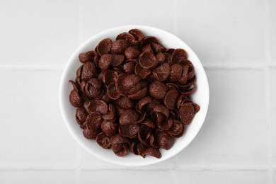 Photo of Breakfast cereal. Chocolate corn flakes in bowl on white tiled table, top view