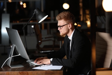 Photo of Concentrated young businessman working in office alone at night