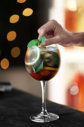 Photo of Woman preparing fresh alcoholic cocktail with lemon and mint at bar counter, closeup