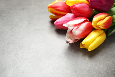 Photo of Beautiful spring tulips on grey stone table, closeup. Space for text