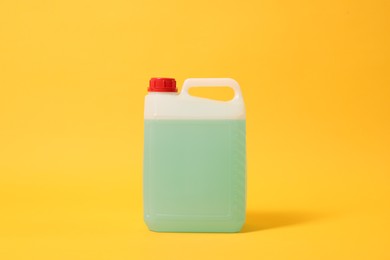 Photo of Plastic canister with green liquid on orange background