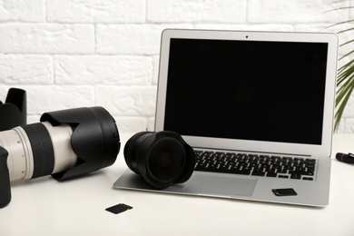 Photo of Laptop and professional photographer's equipment on table indoors. Space for text