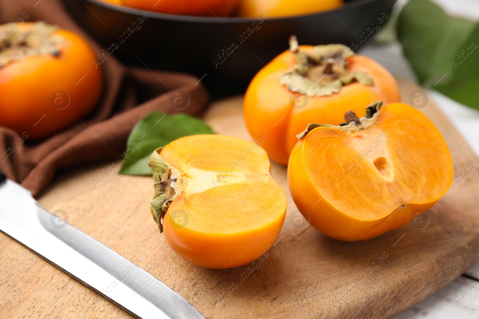 Photo of Whole and cut delicious ripe persimmons on table, closeup