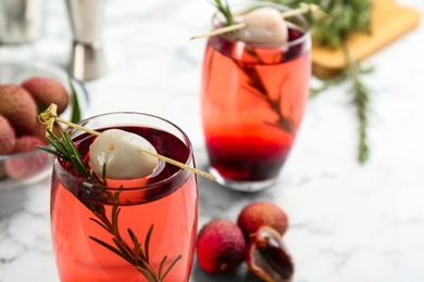 Photo of Delicious lychee cocktail with rosemary on white  table, closeup. Space for text