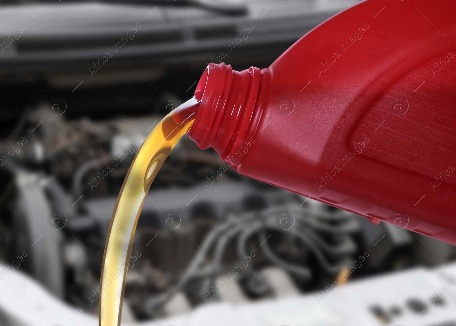 Image of Pouring motor oil from red container, closeup