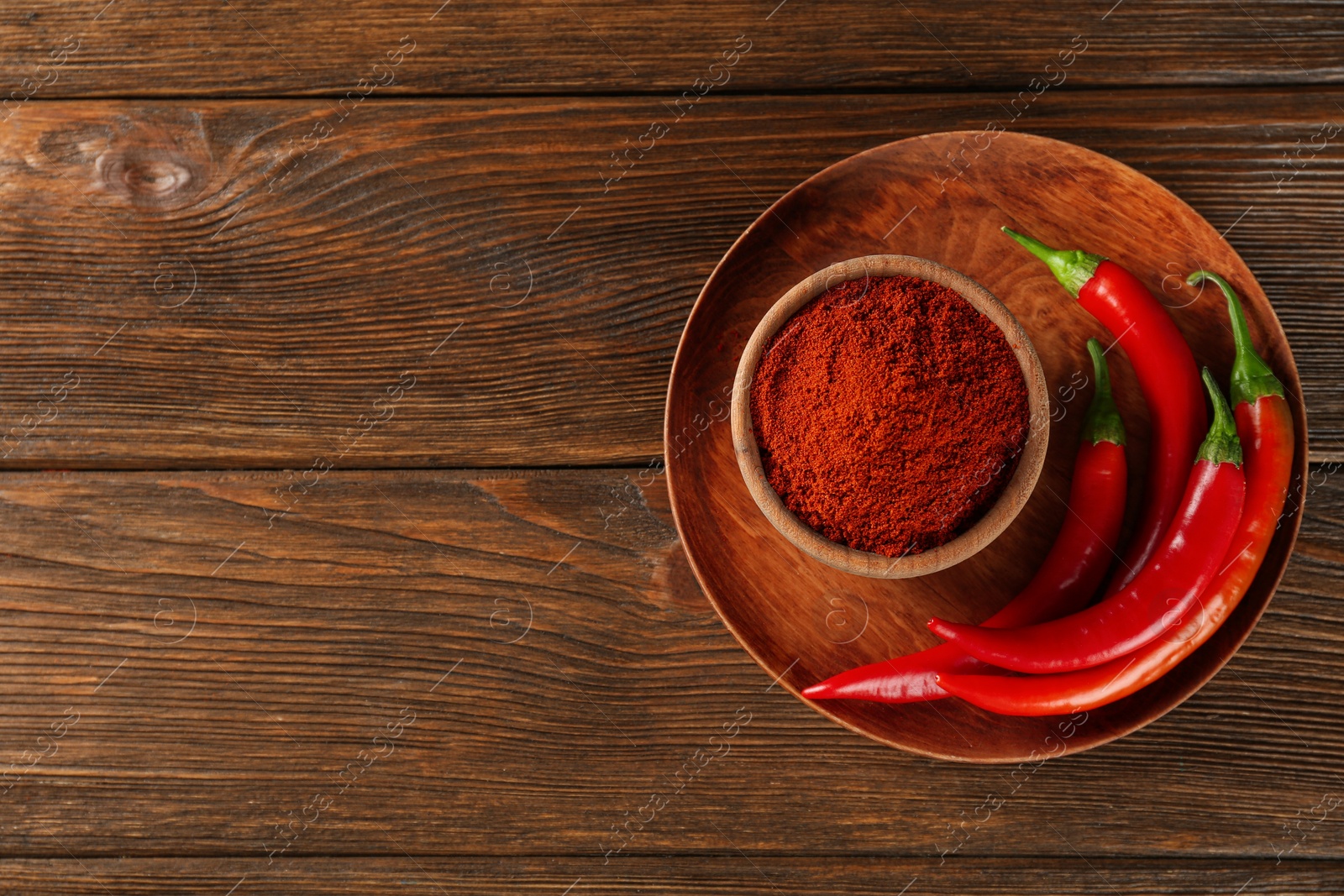 Photo of Paprika powder and fresh chili peppers on wooden table, top view. Space for text