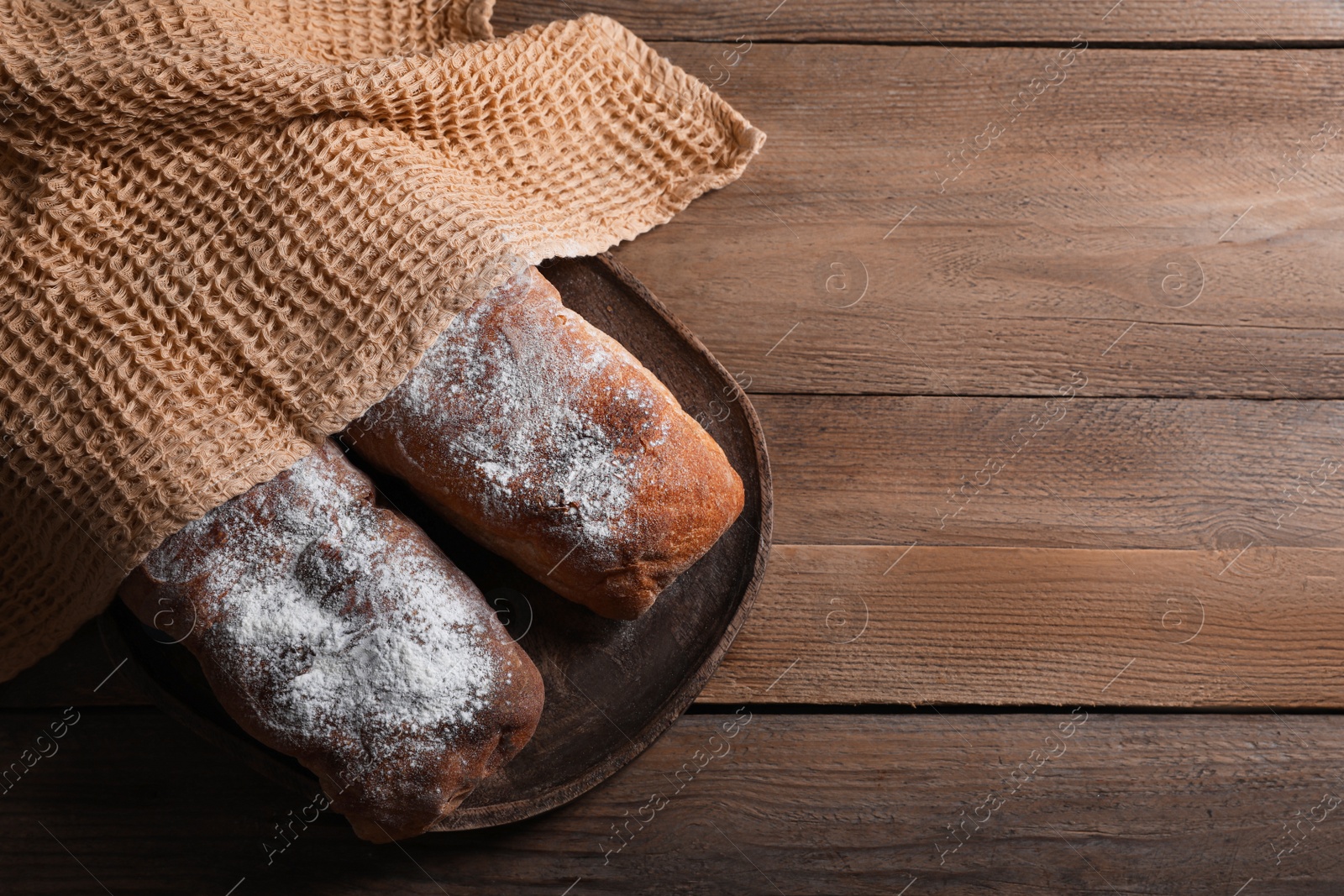 Photo of Fresh crispy ciabattas on wooden table, flat lay. Space for text