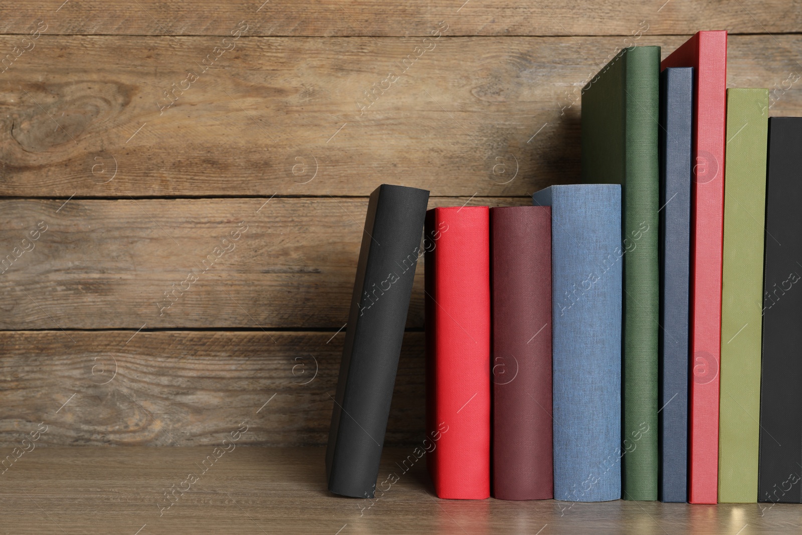 Photo of Many hardcover books on wooden table, space for text