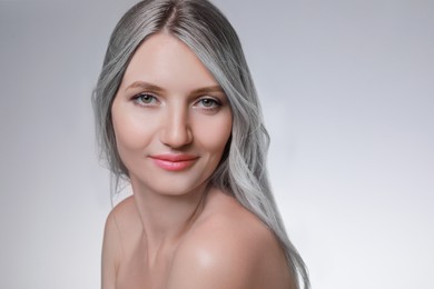 Image of Portrait of beautiful woman with ash hair color on light grey background