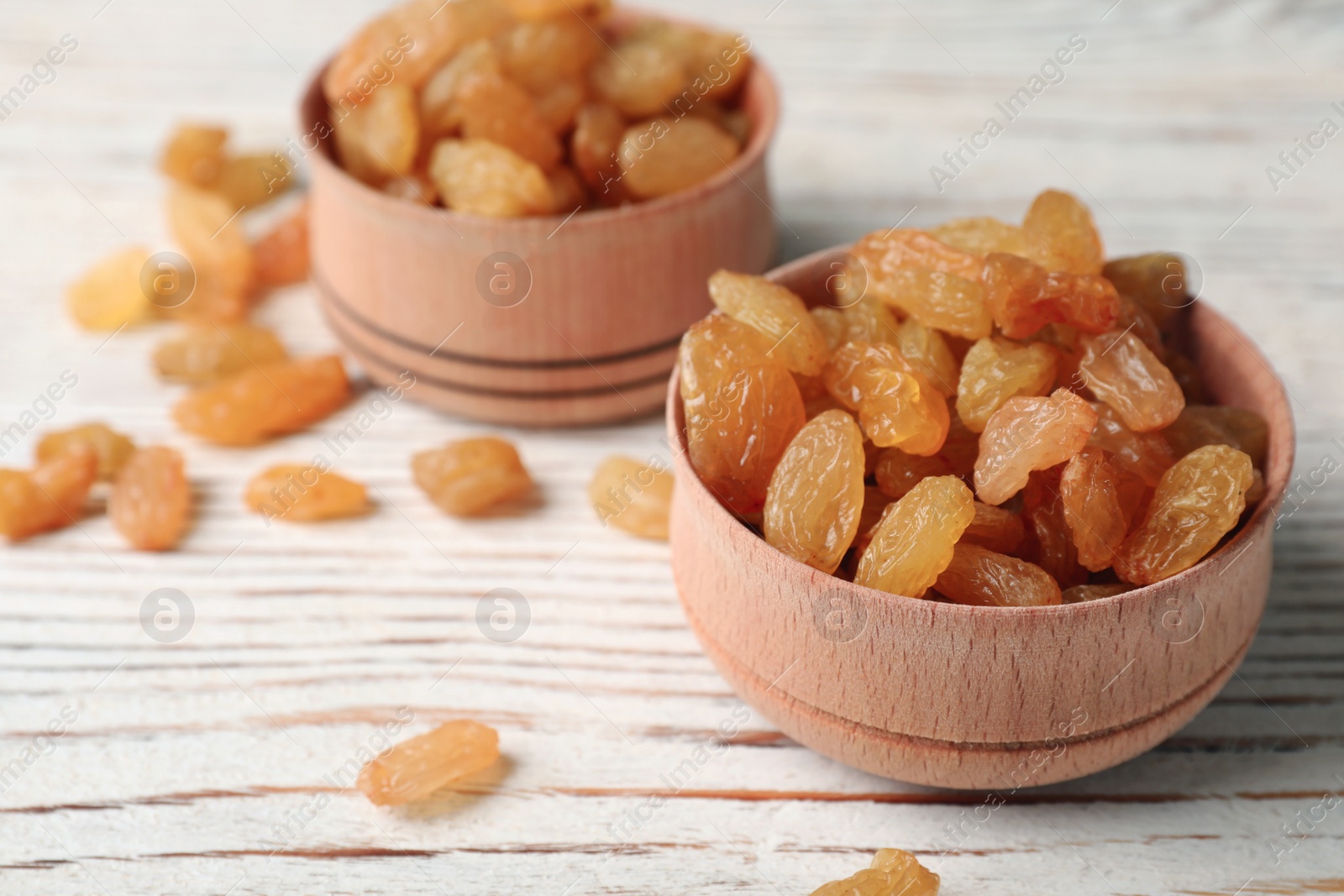 Photo of Bowls with raisins on wooden table, space for text. Dried fruit as healthy snack