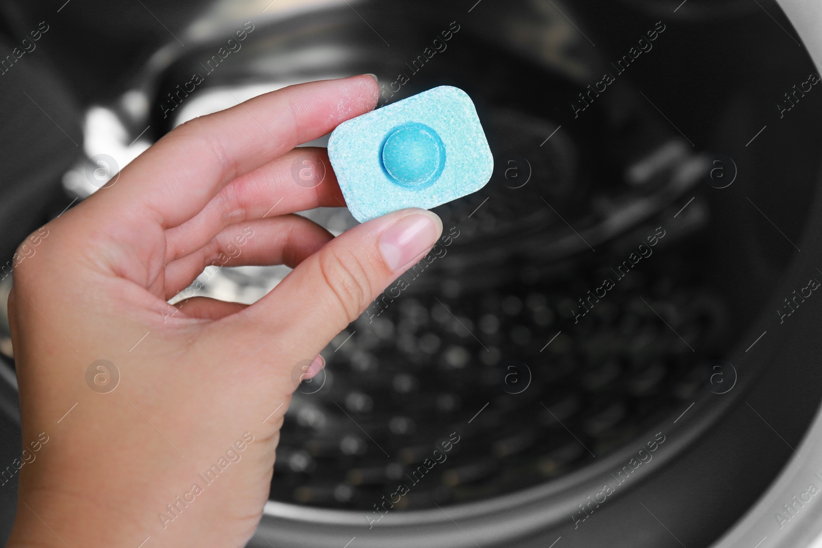 Photo of Woman putting water softener tablet into washing machine, closeup