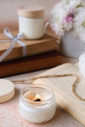 Photo of Burning candle and book on beige textured table