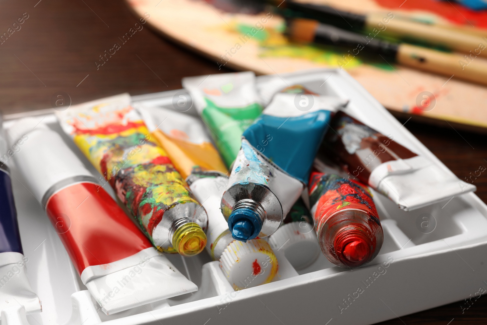 Photo of Pack of tubes with oil paints on wooden table, closeup